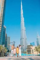 glückliche familie, die in dubai mit wolkenkratzern im hintergrund geht. foto