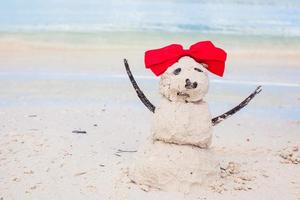 kleiner sandiger Schneemann mit Schleife am weißen karibischen Strand foto