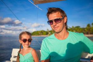 Kleines entzückendes Mädchen mit jungem Vater entspannen sich beim Segeln auf dem Boot foto