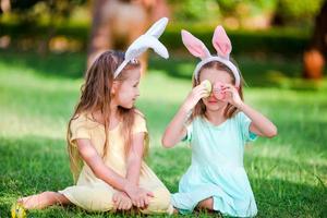 Zwei kleine Mädchen mit Hasenohren zu Ostern im Freien foto