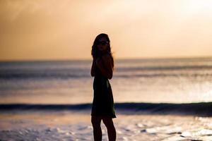 schöne Frau am weißen Strand bei Sonnenuntergang. foto