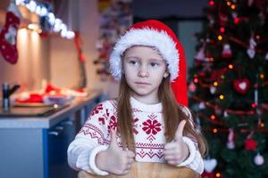 entzückendes kleines mädchen, das lebkuchenkekse für weihnachten in der küche backt foto