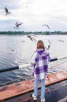 Süßes kleines Mädchen füttert Möwen foto