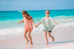 Entzückende kleine Mädchen haben gemeinsam Spaß am weißen tropischen Strand foto