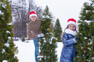 glücklicher vater und kind in weihnachtsmützen mit weihnachtsbaum im freien foto