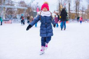 entzückendes kleines Mädchen, das auf der Eisbahn Schlittschuh läuft foto