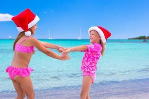 kleine entzückende mädchen in weihnachtsmützen während des strandurlaubs foto