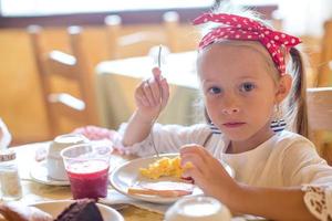 entzückendes kleines Mädchen, das im Restaurant frühstückt foto