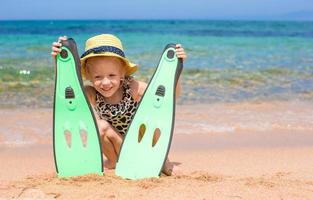 kleines mädchen mit flossen und brille zum schnorcheln am strand foto