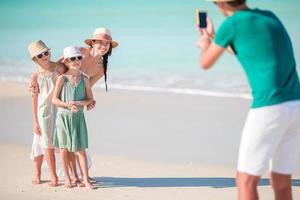 Mann fotografiert seine Familie am Strand. Familienstrandurlaub foto