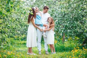 entzückende familie im blühenden kirschgarten am schönen frühlingstag foto