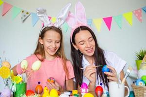 Mutter und ihre kleine Tochter malen Eier. glückliche familie, die sich auf ostern vorbereitet. foto