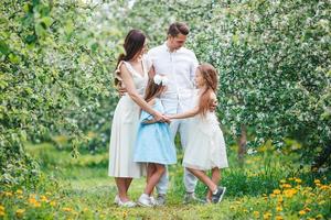 entzückende familie im blühenden kirschgarten am schönen frühlingstag foto