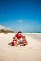 Vater und seine entzückenden kleinen Töchter, die am Strand spielen foto