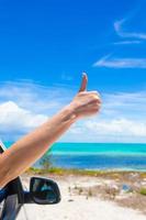 weibliche Hand zeigt Daumen nach oben am Strand foto