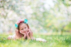 entzückendes kleines Mädchen im blühenden Apfelbaumgarten am Frühlingstag foto