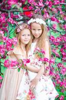 Entzückende kleine Mädchen im blühenden Apfelbaumgarten am Frühlingstag foto