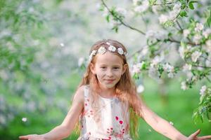 entzückendes kleines Mädchen im blühenden Apfelbaumgarten am Frühlingstag foto