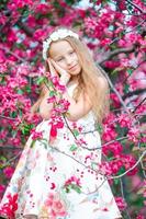 Entzückendes kleines Mädchen im blühenden Apfelbaumgarten am Frühlingstag foto
