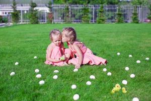 ältere schwester küsst jüngere auf einem grünen gras aus ostereiern foto