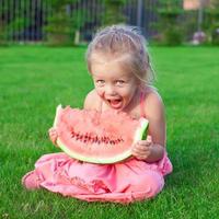 kleines entzückendes mädchen mit einem stück wassermelone in den händen foto