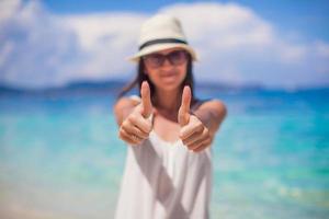 junge schöne Frau zeigt Daumen nach oben am Strand foto