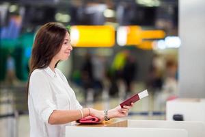 glückliche Frau mit Tickets und Pässen am Flughafen, die auf das Boarding warten foto