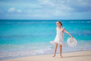 schönes kleines Mädchen im Kleid am Strand, das Spaß hat. foto
