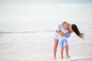 schöne Mutter und Tochter am weißen Strand foto