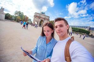 glückliche junge familie mit stadtplan, der selfie in paris im freien macht foto