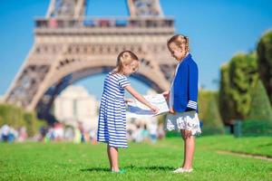 entzückende kleine mädchen mit karte von paris im hintergrund der eiffelturm foto