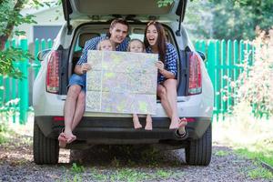 familie mit zwei kindern, die sich die karte ansehen, während sie mit dem auto unterwegs sind foto