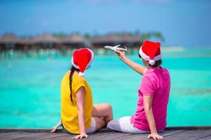 junges paar in weihnachtsmützen, die sich während der weihnachtsferien am strand entspannen foto