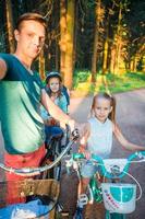 glückliche Familie, die draußen im Park radelt foto