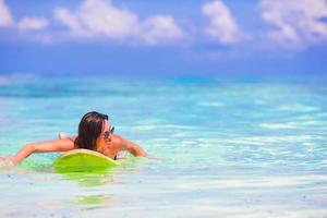 glückliche junge surffrau, die mit einem surfbrett am strand läuft foto