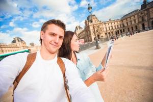 glückliches junges paar mit stadtplan, der selfie in paris im freien macht foto