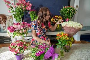 junge schöne Frau in Blumen des Zimmers foto