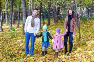 Eine vierköpfige Familie geht an einem sonnigen, warmen Tag im Herbstpark spazieren foto