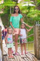 junge Mutter mit ihren kleinen Mädchen auf der Hängebrücke über den Fluss Loboc, Philippinen foto