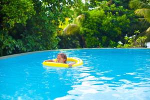 Kleines Mädchen schwimmt in einem Gummiring am Pool foto