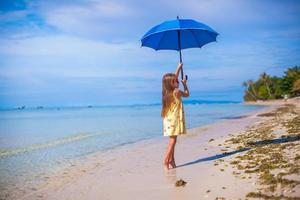 kleines Mädchen mit Sonnenschirm am exotischen Strand foto