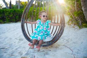 glückliches kleines Mädchen genießen Schaukel am weißen Sandstrand der Karibik foto