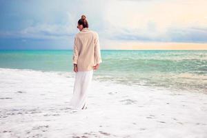 Frau, die am Strand liegt und die Sommerferien mit Blick auf das Meer genießt foto