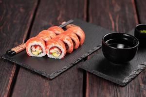 Sushi-Rolle Maguro mit Thunfisch, geräuchertem Aal, Avocado, Philadelphia-Käse auf schwarzem Brett. Sushi-Menü. japanisches Essen. foto