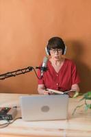 Porträt einer reifen Frau, die Kopfhörer trägt und bei einem Online-Radiosender spricht - Podcast- und Broadcast-Konzept foto