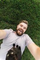 mann mit kleinem kätzchen, das auf gras liegt und spielt - freundschaftsliebestiere und haustierbesitzerkonzept foto