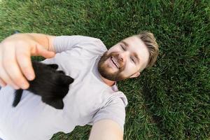 mann mit kleinem kätzchen, das auf gras liegt und spielt - freundschaftsliebestiere und haustierbesitzerkonzept foto