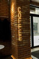 kaffee-leuchtreklamemblem im neonstil auf backsteinmauerhintergrund. Café foto