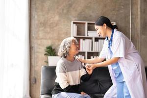 junge Pflegekraft hilft Seniorin beim Gehen. krankenschwester unterstützt ihre alte patientin im pflegeheim. Seniorin mit Spazierstock, der zu Hause von einer Krankenschwester geholfen wird. foto