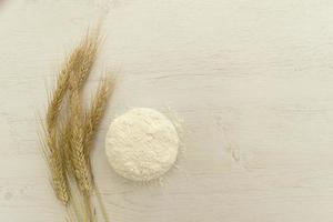 Bündel Weizenähre und Mehl auf weißem Holztisch. foto